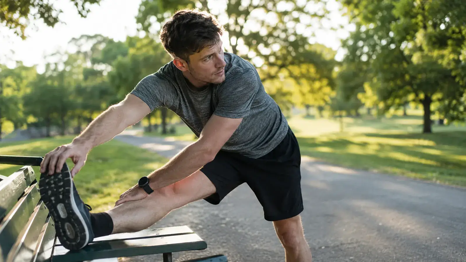 Runner stretching hamstrings on a park bench after a morning run